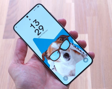 Samsung Galaxy S25 showing the lockscreen held in a hand above a table.