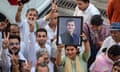 People give the V sign and hold up a framed photograph of Rahul Gandhi