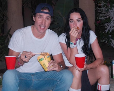 Justin Trudeau and Katy Perry sit outdoors at night, eating noodles with red plastic cups