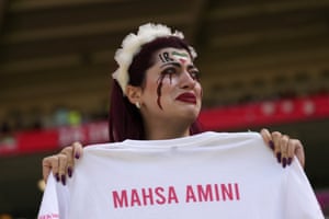 An Iran supporter cries as she holds a shirt which reads Mahsa Amini before the start of the match between Wales and Iran at the Ahmad bin Ali stadium in Al Rayyan