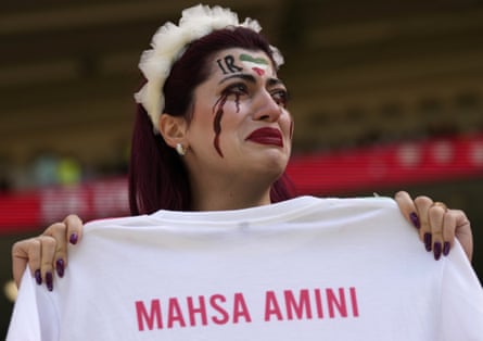 A female fan holds up a jersey bearing the name of Mahsa Amini, the Iranian girl who recently died in suspicious circumstances after being arrested by police for not wearing her hijab