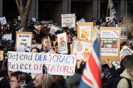 Protesters hold signs with slogans including 'Defend Democracy, Reject Dictators' and 'Bow to China Lose Forever'.