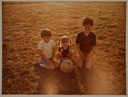 An old photograph of two young boys and a girl kneeling on a pitch with a football, bathed in yellow light