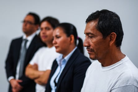 A line of three men and one woman, inside a room looking towards something we cannot see.