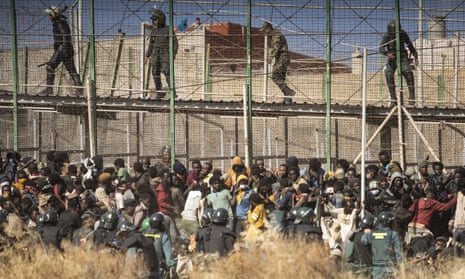 Riot police and migrants at the border between Morocco and the Spanish enclave of Melilla, June 2022