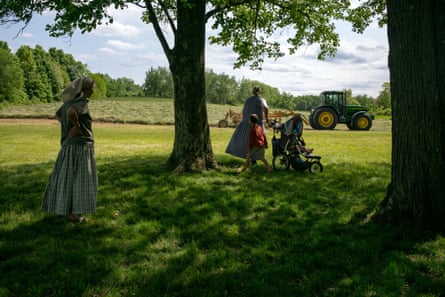 A family watches the tractor work the fields on the farm in the Foxhill community, Upstate NY