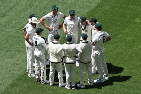 Pat Cummins speaks to his teammates in a huddle on the pitch