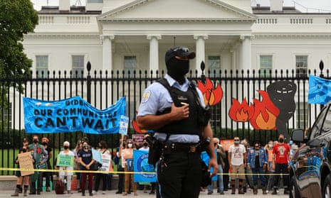 Demonstrators, including members of the Sunrise Movement, rally outside the White House for climate justice as a police officer keeps watch on 13 October.