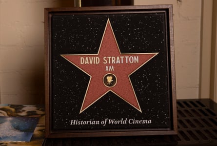 A plaque given to David Stratton sits on the wood flue stove in his living room, a gift from his former students.