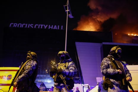 Russian law enforcement officers stand guard near the burning Crocus City Hall concert venue.