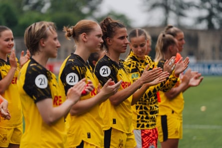 Borussia Dortmund players stand in a line and applaud.