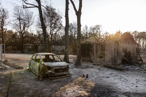 A burnt out car in an area scorched by a wildfire.