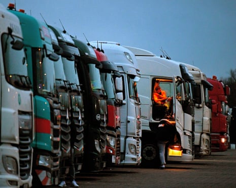 Drivers of freight lorries and heavy goods vehicles are illuminated by the lights inside their cabs as they are parked at a truck stop off the M20 leading to Dover.