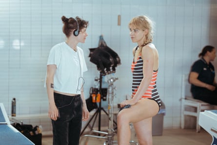 Kristen Stewart on set wearing headphones and talking to Imogen Poots who is wearing a swimming costume