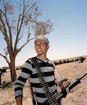 Man standing in desert with automatic weapon and magazine of bullets