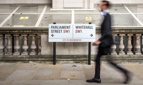 A blurred civil servant walking past a street sign for Parliament Street and Whitehall in London