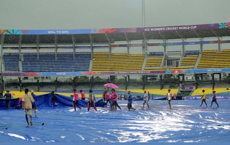 General view inside the stadium as ground staff members bring out covers after rain interrupts play