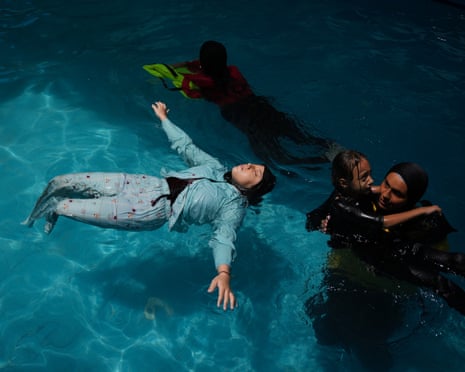 Rimas, a teen who lost both legs, floats on her back during swimming training in a pool