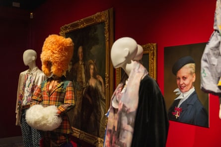 Rebel-Storyteller-Visionary retropsective exhibition at The Bowes Musuem, including a Harris tweed jacket, bloomer trousers with sheepskin trim and a hat and muff, worn by a mannequin, between more mannequins wearing further pieces of Westwood’s work. Hung upon the scarlet wall, paintings of Westwood.