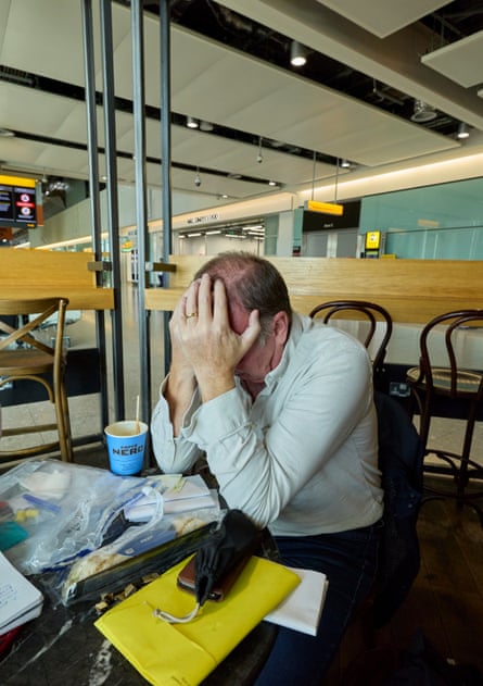 Charles with his head in this hands at a cafe at Heathrow