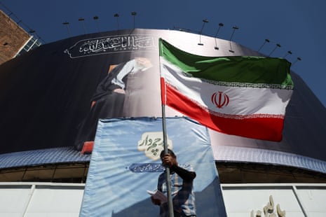 A man holds an Iranian flag on a street in Tehran after news that the US and Iran had come to an initial peace agreement.