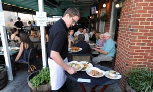 Server with plates on the terrace at Top of the Hill Restaurant, Brewery and Distillery in Chapel Hill, North Carolina, US.