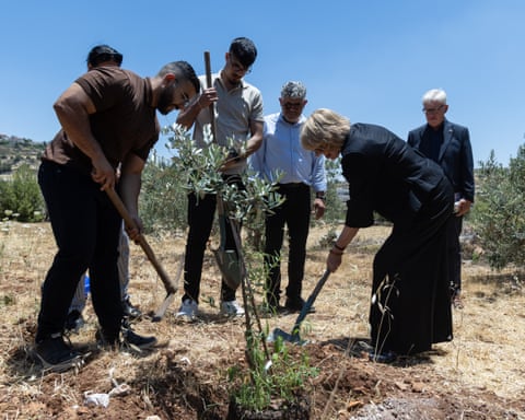 Sarah Mullally shovels earth around a sapling