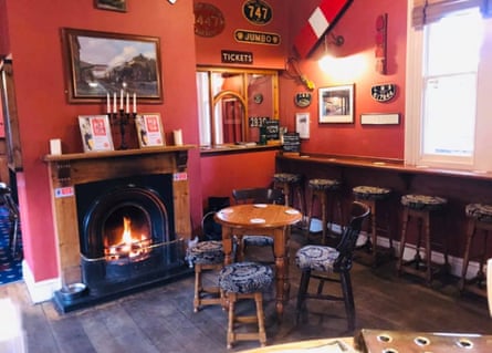 A red pub room with real fire, bar stools and train signage