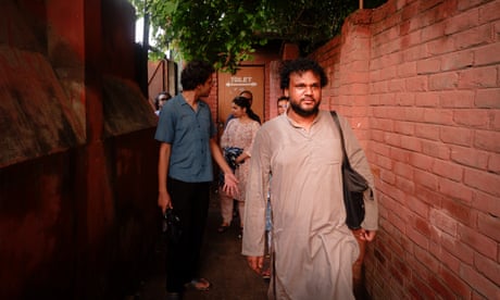 A man in a shalwar kameez leads a group along an alleyway