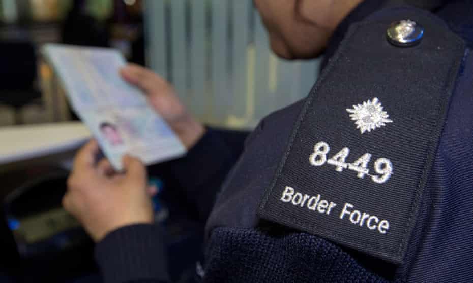A Border Force officer checks the passport of a passenger at Heathrow airport.