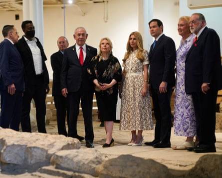 The dignitaries stand in a row with a low wall in the foreground