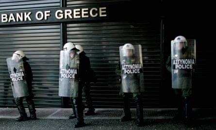 Riot police line up outside a closed branch of the National Bank of Greece during a general strike in protest against austerity measures .