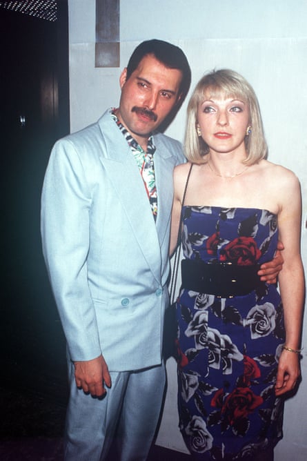 A man in a light-blue suit with his arm around a blond woman wearing a blue printed dress.