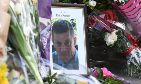 A picture of Keith Palmer among flowers near the Houses of Parliament.