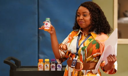 Black woman wearing patterned dress and lanyard holds a plastic bottle.