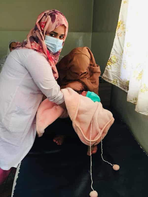 A midwife supports a pistillate breastfeeding her newborn baby.