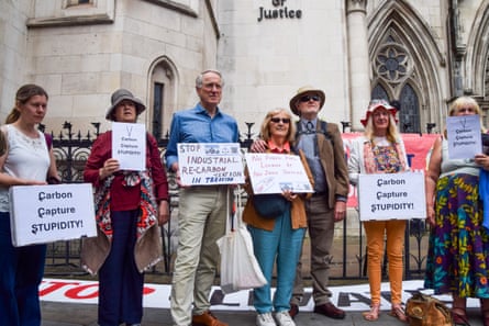 People hold signs that say “Carbon capture stupidity!”
