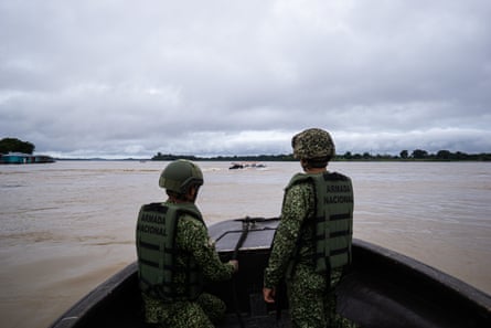 Two soldiers in a boat looking out on to the river
