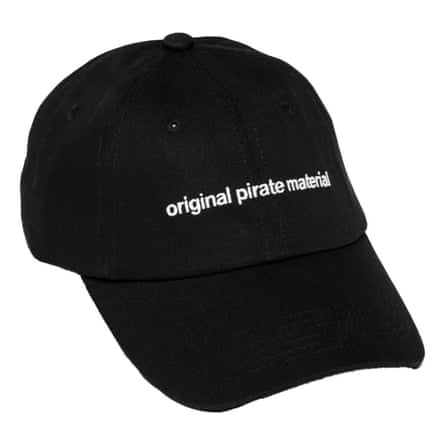 A black baseball cap on a white background. It has the words original pirate material across it.