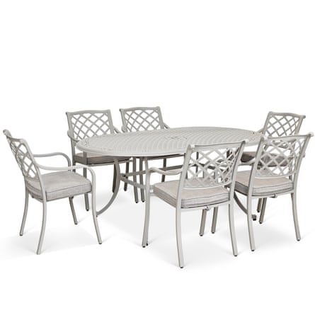 A rounded end metal table is surrounded by 6 metal chairs that have a lattice pattern back.