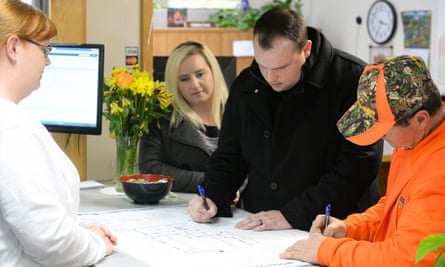 Jason Buzzard, center, and his contractor Jon Hornback, right, sign their permit paperwork as Meagann Buzzard (left) watches at Paradise town hall on 28 March.