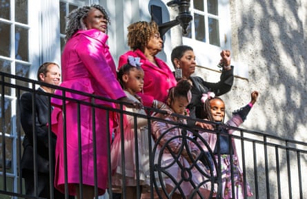 three women and three children stand on a balcony