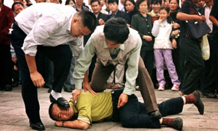 Police detain a Falun Gong protester in Tiananmen Square as a crowd watches in Beijing, in 2000.