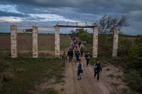 Migrants are escorted by members of the Texas Army National Guard after crossing the Rio Grande river into the US from Mexico