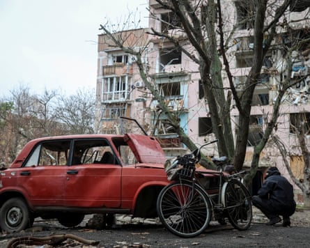A resident hides from a Russian FPV drone behind a damaged car in the frontline town of Huliaipole