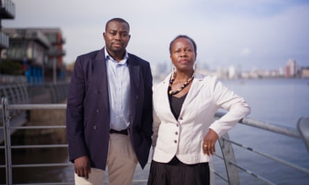 A man and a woman stand on a balcony overlooking a river.