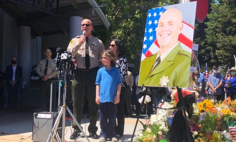 The Santa Cruz sheriff, Jim Hart, stands next to a photo of fallen Sgt Damon Gutzwiller, who was shot and killed in Ben Lomond.