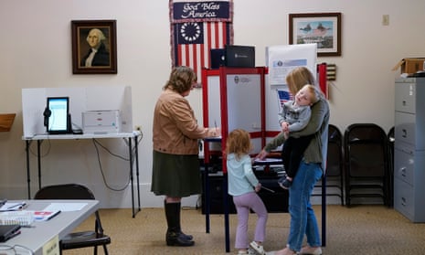 Lauren Miracle, right, holds her son Dawson, 1, as she helps her daughter Oaklynn, 3, fill out a child's practice ballot before voting herself at a polling location in the Washington Township House in Oregonia, Ohio, Tuesday, Nov. 7.