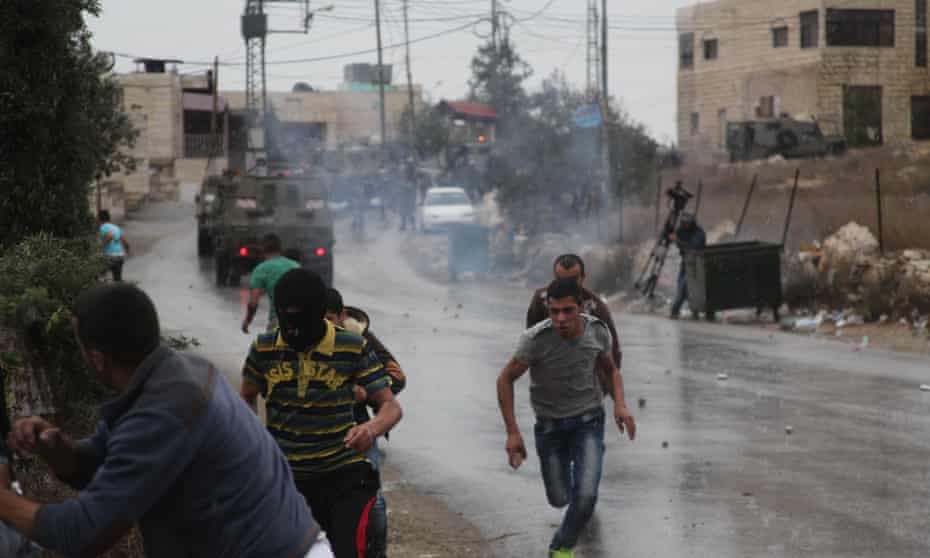 Palestinian protesters run from teargas fired by Israeli soldiers during clashes in the West Bank.