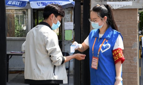 A volunteer checks a resident’s temperature at the entrance of a community in Haidian district in Beijing.